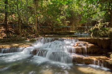 Fototapeta premium Tropical limestone tiered waterfall flowing through green rainforest with emerald natural pool
