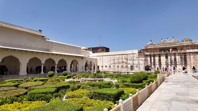 A white courtyard building with arched colonnades and a meticulously kept garden.