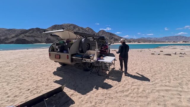 Setting up a teardrop camper on the beach in Baja California, preparing meals as the sun rises over the Sea of Cortez.