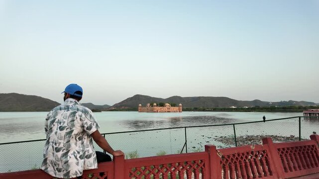 A man with a blue cap admires Jal Mahal from a viewing platform.