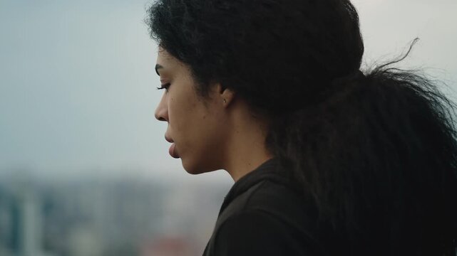 Sad African American woman looking at city from high rise building, acrophobia