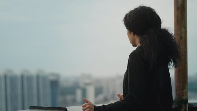 African American woman looking at cityscape from rooftop, afraid of heights