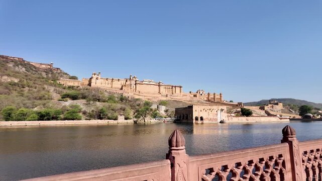 Amber Fort overlooks a lake under a clear blue sky.