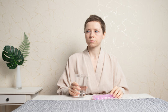 woman holding a water glass while her hand rests on a weekly pill organizer, symbolizing long-term endocrine therapy, health monitoring and disciplined home routine