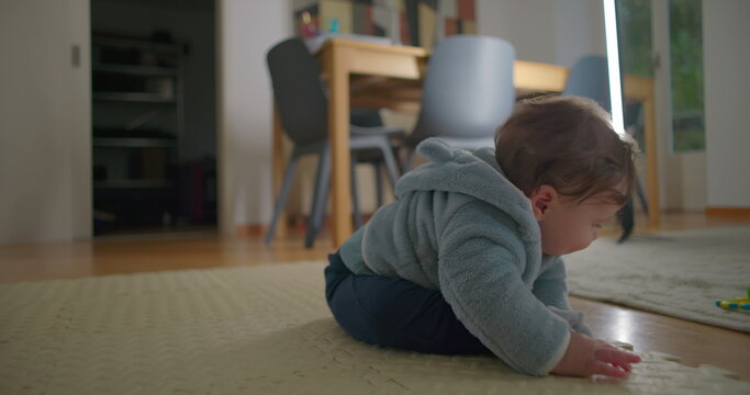 Baby bending forward on mat touching floor with hands in quiet home interior, focused on movement and balance, concept of early coordination, curiosity, and motor exploration