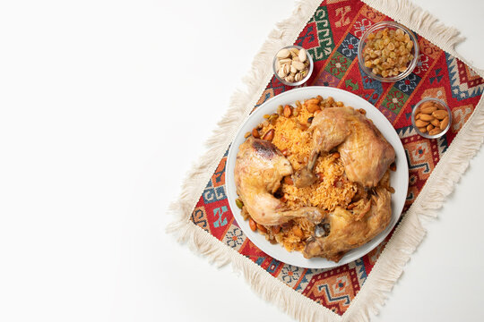 roasted chicken served over spiced rice with almonds pistachios and raisins on a patterned textile