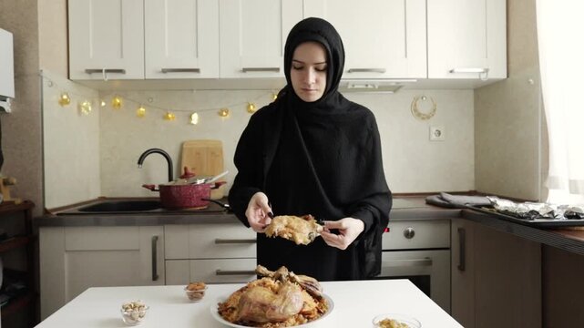 muslim woman in black hijab standing in home kitchen with white dallah and finjan cups prepared for arabic coffee service during ramadan