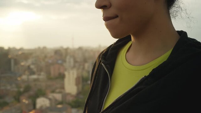 Lonely Black woman looking at city from rooftop, thinking about family