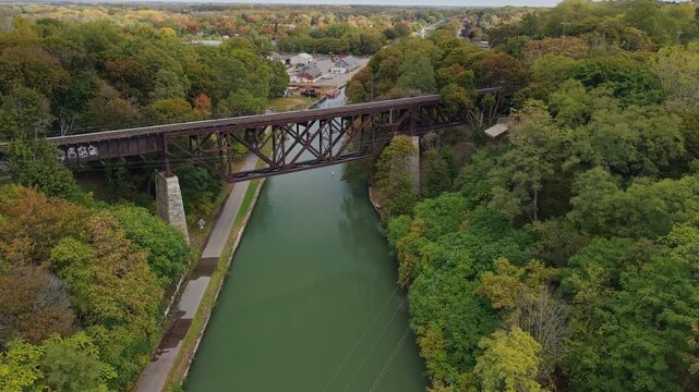 Lockport, New York, USA. Historic Upside Down Railroad Bridge crossing the Erie Canal in Lockport with forested banks and canal towpath, scenic aerial view