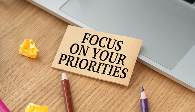 Focused note rests on wooden desk beside laptop. Colored pencils and sticky notes hint at planning or creativity.