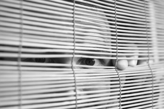 Through wooden blinds the man looks