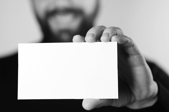small white piece of paper in his hand man monochrome