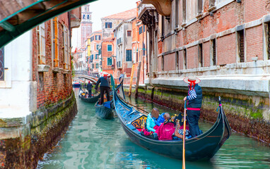 Venetian gondolier punting gondola through green canal waters of Venice, Italy © muratart