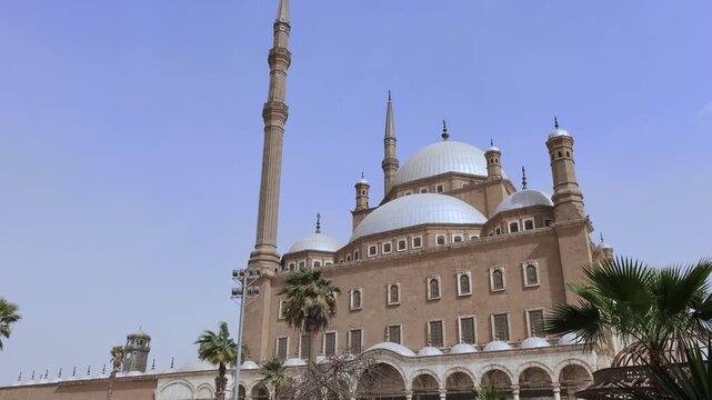 Wide shot of Muhammad Ali Mosque complex, Cairo Citadel, Egypt, with large central dome flanked by smaller domes, decorative minarets and colonnaded entrance portico.