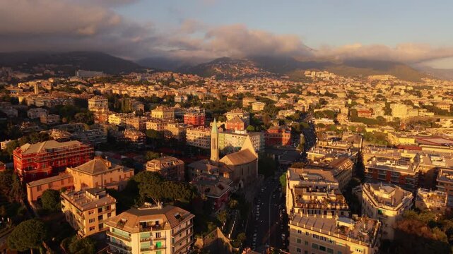 Drone flying over Genoa highlighting San Francesco da Paola church at sunset with hills behind