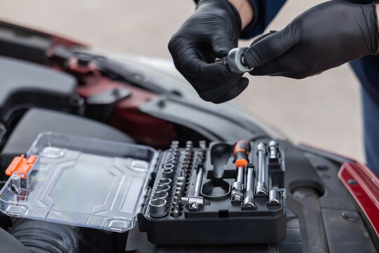 Hands selecting socket tool from kit for vehicle repair and maintenance work