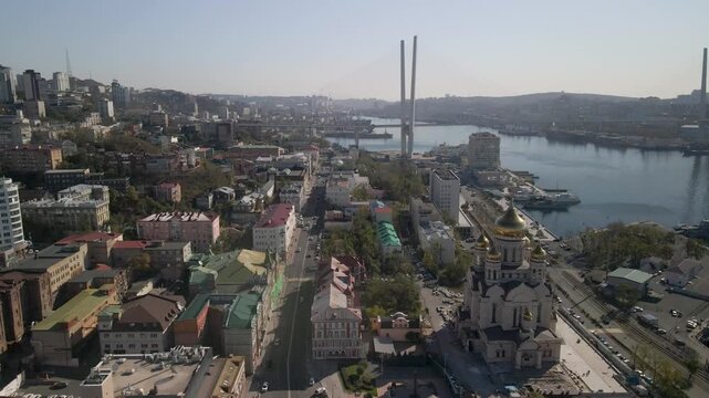 The video captures the cityscape of Vladivostok with Zolotoy Rog Bay, the Golden Bridge, and the central cathedral.
