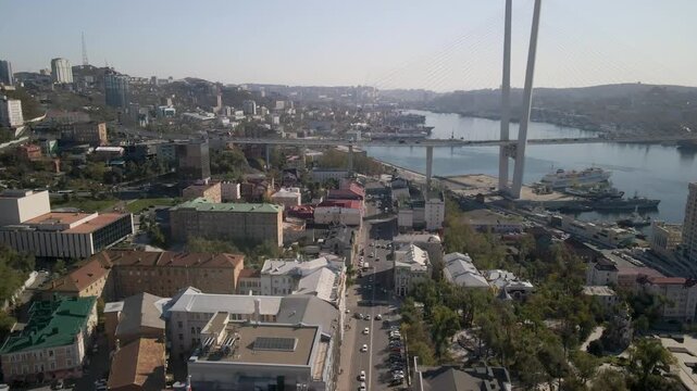 Drone view of the Golden Bridge over Zolotoy Rog Bay, with ships, buildings, and the urban landscape of Vladivostok.