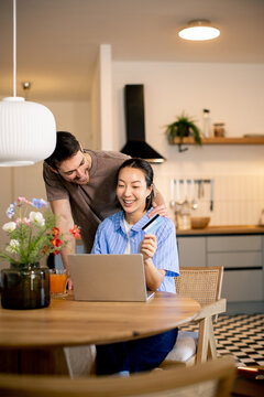 Couple spends time together at home while using a laptop in a cozy kitchen space