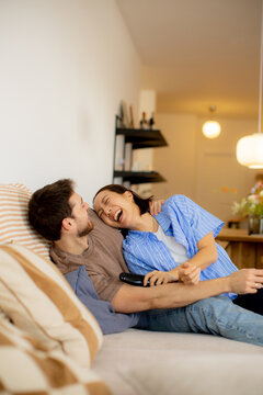 Korean woman and Caucasian man share fun moments on couch in cozy living room