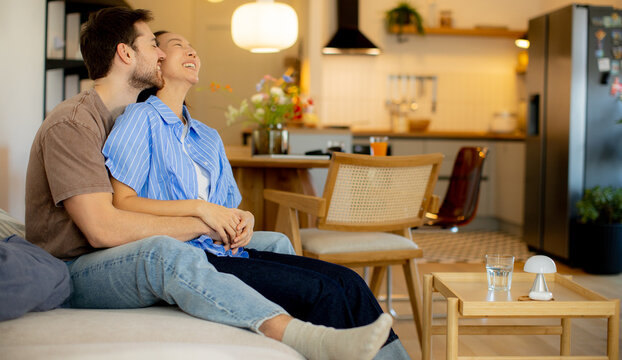 Korean woman and Caucasian man relax at home in a cozy setting during a sunny afternoon