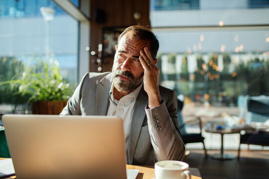 Stressed businessman working on laptop in coffee shop