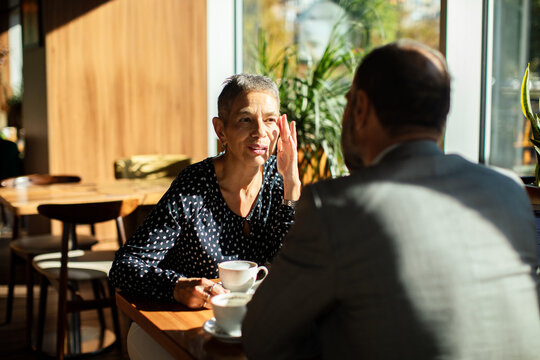 Mature woman and man meeting over coffee in a sunlit cafe