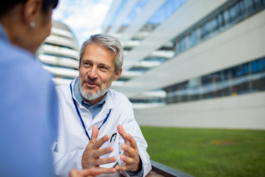 Senior doctor consulting colleague outside hospital