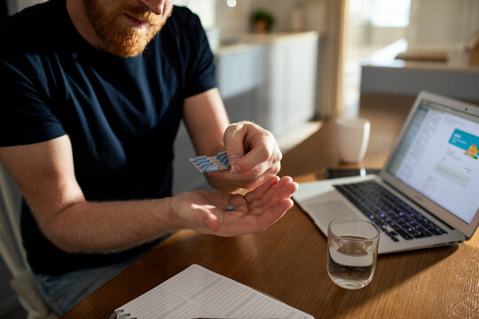 Man taking medication at home office desk