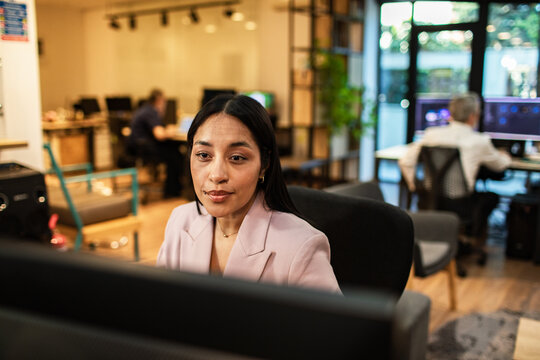 Focused businesswoman working at computer in modern coworking office