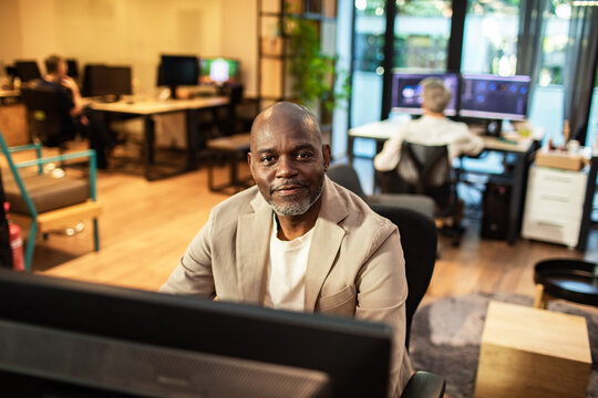 Confident mature man working at computer in modern open office