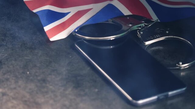 Mobile phone evidence and police handcuffs and British flag with smoke on desk