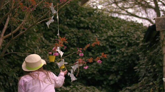 Woman wearing Easter bonnet and sits by easter decorations on blossom tree