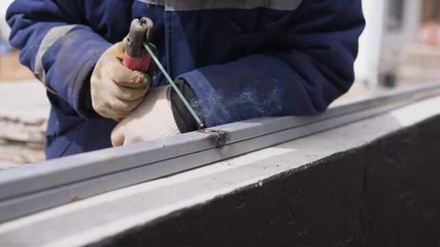 Professional Welder Is Working On Steel Beams Amidst Sparks At Construction Site. An Experienced Construction Worker Is Performing Precise Metal Welding While Sparks Illuminate Area