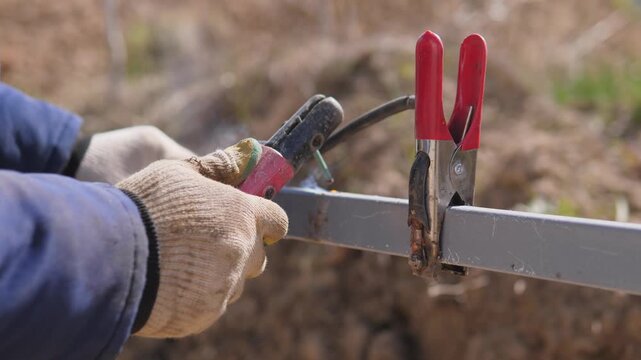 Qualified Welder Assembles Metal Outdoors. Electric Arc Technician Performing Work Outside. Electric Arc Welding Carried Out By Experienced Professional On Outdoor Building Locations