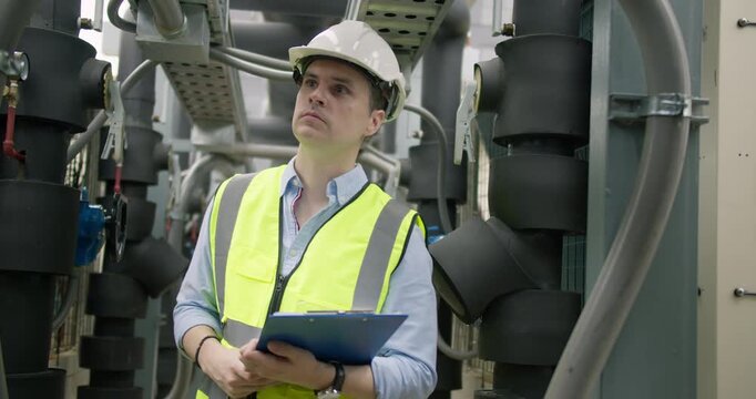 An engineer inspects HVAC system pipes in a plant room, performing quality control and system maintenance for optimal building performance and efficiency.
