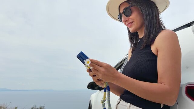 Close up Portrait of pretty happy woman using her smartphone type, chat, planning trip use social media overseas. Mediterranean coastline. Concept mobile roaming, connectivity, data esim 5g coverage