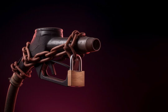 Black fuel pump nozzle wrapped in rusty chains and secured with a brass padlock on a dark red background symbolizing energy crisis and fuel shortage