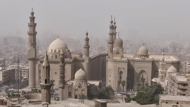 Historic mosques with tall minarets and grand domes dominate the hazy Cairo cityscape, Egypt, showcasing stunning Mamluk Islamic architecture from the medieval period.