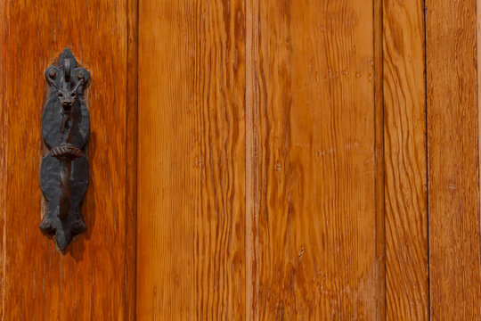 Vintage zoomorphic wrought iron door handle on rustic orange wood with copy space