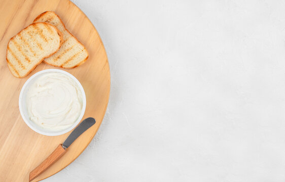 Cream cheese with toasted bread and knife on wooden board breakfast concept with copy space