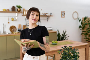 Young woman captures inspiration in her beautiful home kitchen while writing in her journal © LIGHTFIELD STUDIOS