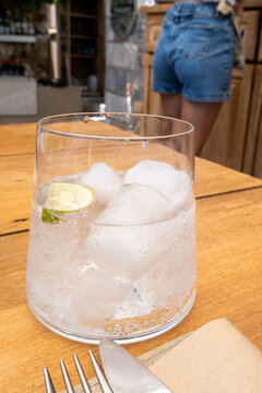Glass of water with lime on the table with blurred waitress in background