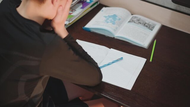 Young boy intensely examining workbook. Child focused on his educational reading material. Child attentively exploring his open educational workbook surrounded by learning materials and supplies