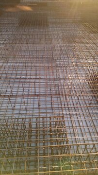 Vertical. Steel reinforcement grid with tied metal rebars ready for pouring concrete into a formwork to create a solid, monolithic slab on a building construction site with the camera moving forward