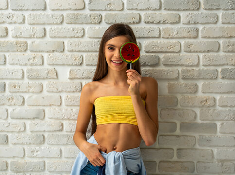 Smiling teen girl with watermelon lollipop.