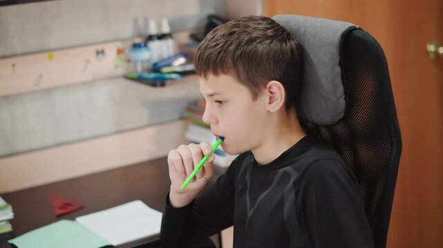 Student preparing diligently. Child studying with focused attention. Young boy immersed in schoolwork at desk. Young student carefully organizing books and notes in welllit study area