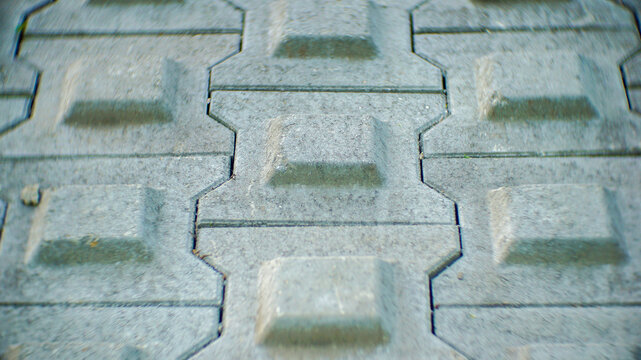Close-up of interlocking concrete pavement tiles with geometric raised rectangular patterns