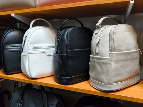 Leather backpacks of different colors are displayed on the shelves of a store