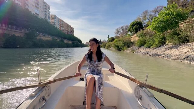 Latin woman paddling canoe on Segura River in Murcia, Spain, smiling and enjoying summer afternoon, travel lifestyle and freedom concept